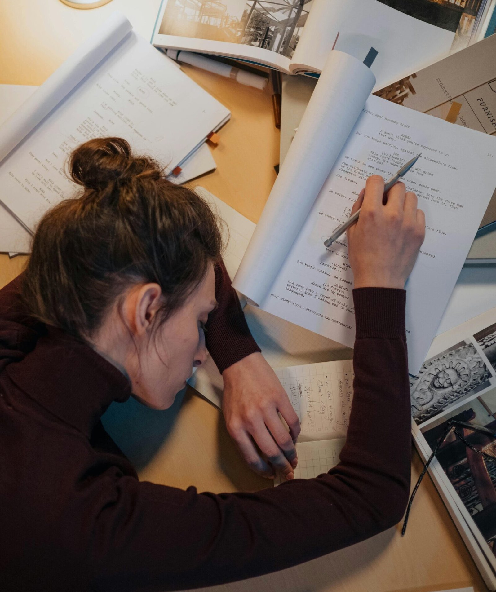 A woman sleeping on a desk surrounded by papers, illustrating stress and overwork.